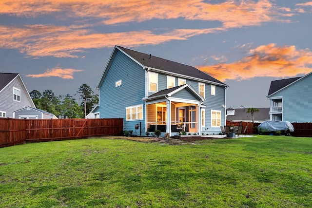 back of house at dusk featuring a sunroom and a patio