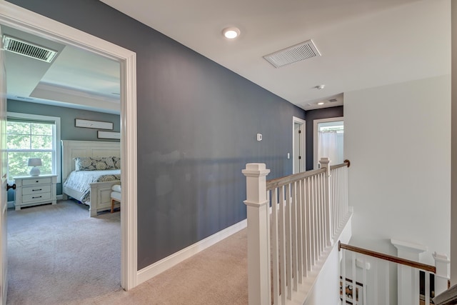hallway with an upstairs landing and carpet flooring