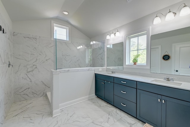 full bath with marble look tiles, a walk in shower, vaulted ceiling, and double vanity