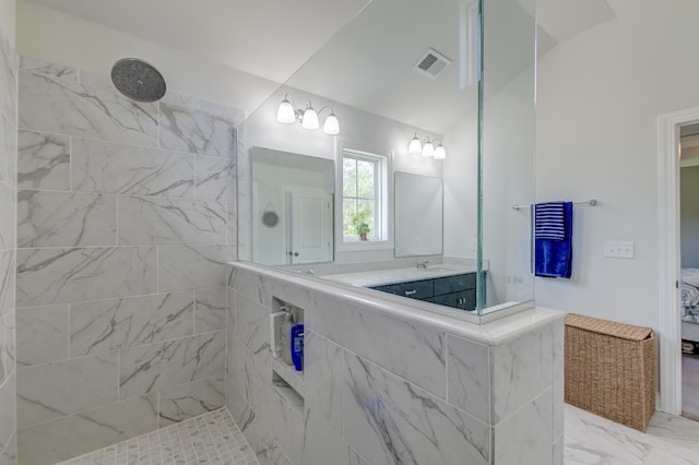 ensuite bathroom with marble look tiles, walk in shower, and vanity