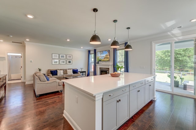 kitchen featuring ornamental molding, dark wood-style floors, a kitchen island, a glass covered fireplace, and recessed lighting