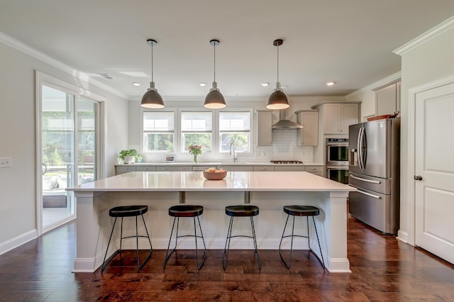 kitchen with stainless steel appliances, a sink, a center island, decorative backsplash, and light countertops
