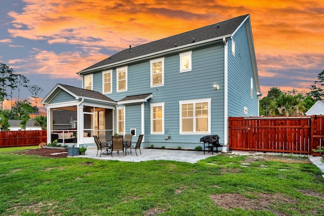 back of house at dusk with a sunroom, a patio, and roof with shingles