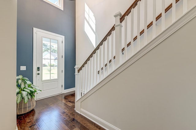 entrance foyer with a towering ceiling, wood-type flooring, stairway, and baseboards