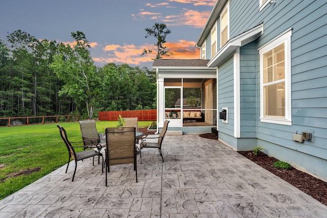 patio terrace at dusk featuring a sunroom and outdoor dining area