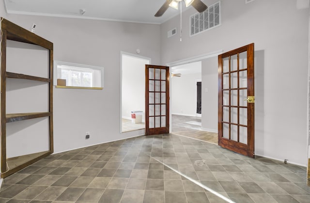 spare room with a towering ceiling, ceiling fan, and french doors