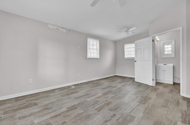 unfurnished bedroom with ceiling fan, ensuite bath, and vaulted ceiling