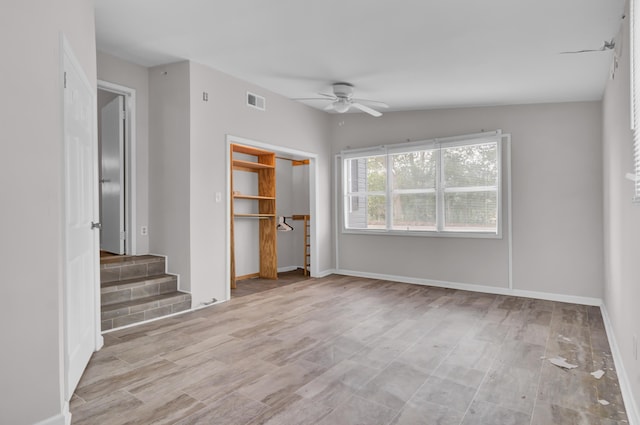 unfurnished bedroom featuring ceiling fan, light hardwood / wood-style floors, vaulted ceiling, and a closet