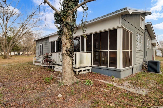 view of side of property with central AC unit, a sunroom, and a wooden deck