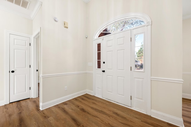 foyer entrance featuring crown molding and dark wood-type flooring