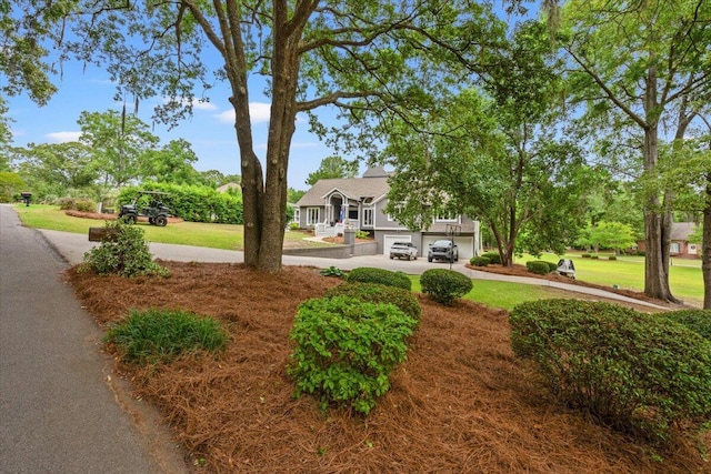 surrounding community featuring concrete driveway, an attached garage, and a yard