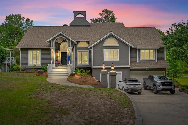 view of front of property featuring driveway, an attached garage, a shingled roof, and a lawn