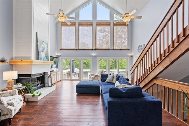 living room with high vaulted ceiling, ceiling fan, healthy amount of natural light, and a large fireplace