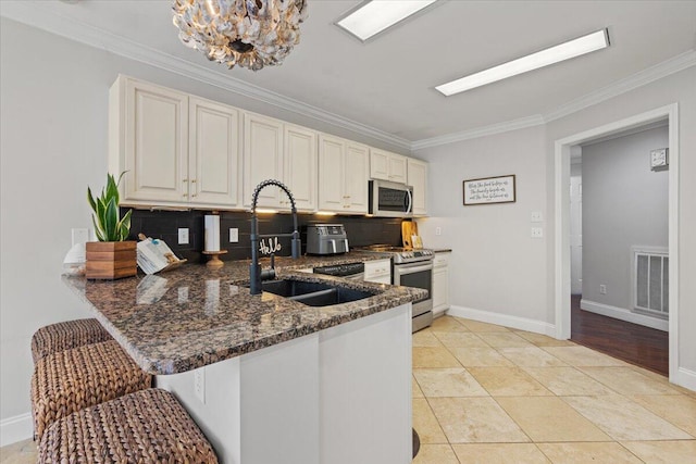 kitchen featuring stainless steel appliances, crown molding, a sink, dark stone counters, and decorative backsplash