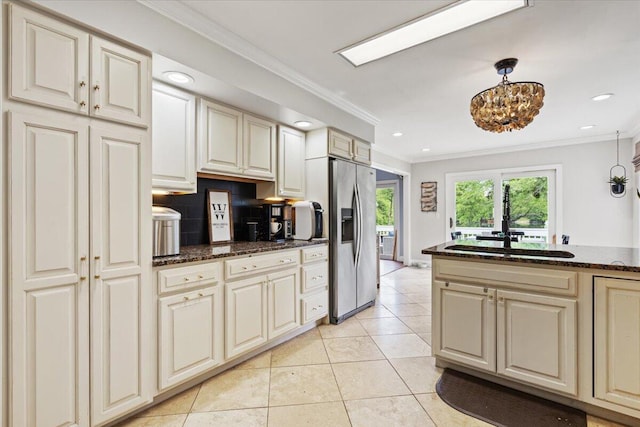 kitchen featuring stainless steel refrigerator with ice dispenser, ornamental molding, a chandelier, recessed lighting, and dark stone countertops