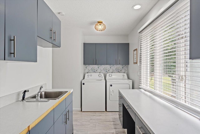 laundry room with cabinet space, separate washer and dryer, a textured ceiling, and light wood-style flooring
