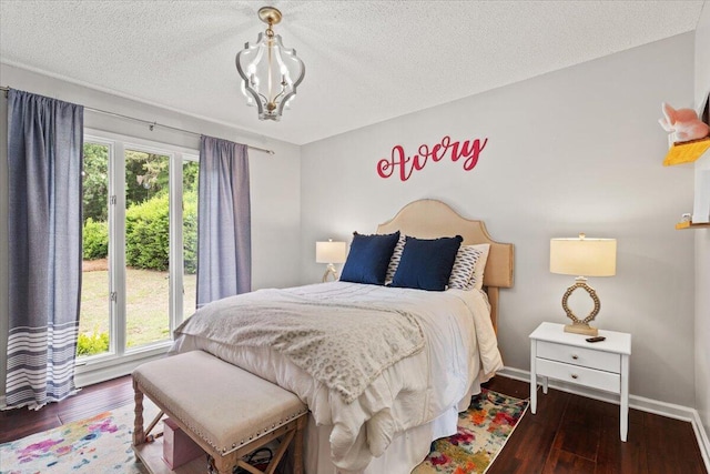 bedroom featuring multiple windows, wood-type flooring, a textured ceiling, and baseboards