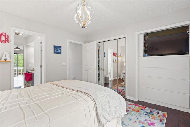 bedroom with dark wood-style flooring, a chandelier, a textured ceiling, and a closet