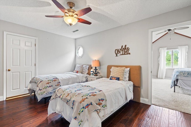 bedroom with dark wood-type flooring, a textured ceiling, and a ceiling fan