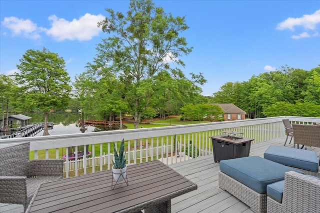 wooden deck with a water view, outdoor dining space, and view of wooded area