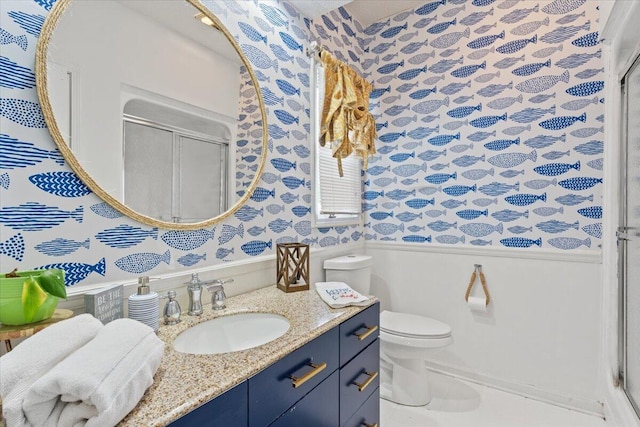 bathroom with wallpapered walls, wainscoting, a stall shower, vanity, and toilet
