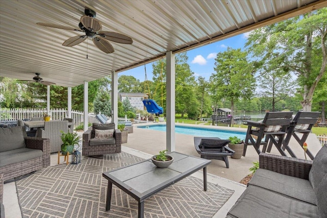 view of patio featuring a ceiling fan, fence, view of wooded area, and an outdoor living space