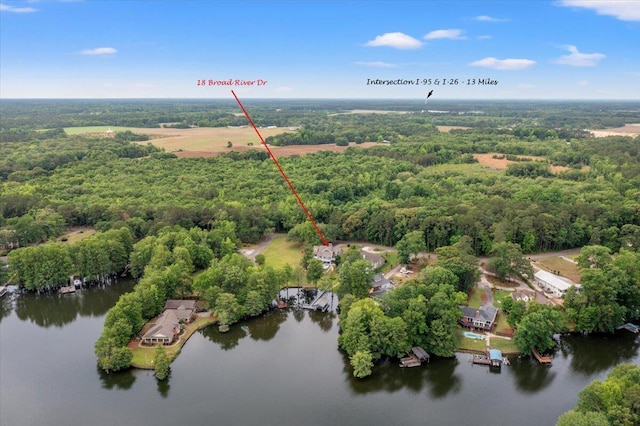 drone / aerial view of a heavily wooded area and a nearby body of water