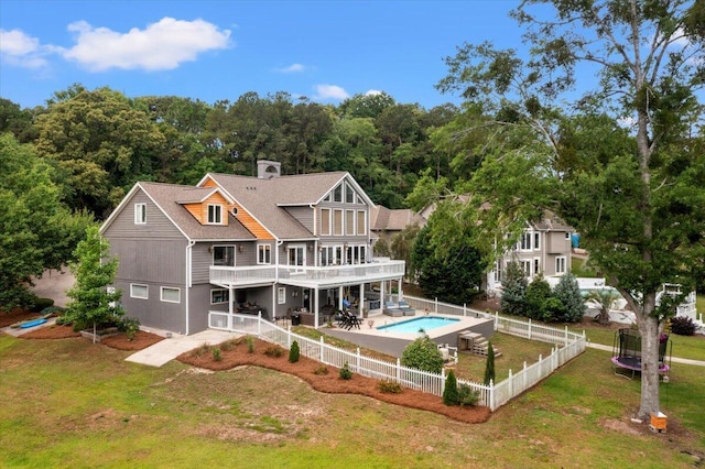rear view of property with a trampoline, a patio area, and a deck