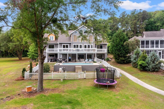 back of property with a trampoline, an outdoor pool, a patio area, and a balcony