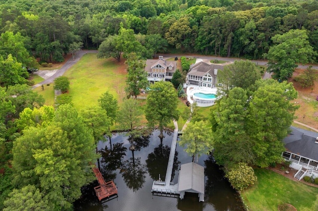 view from above of property with a nearby body of water, a pool, and a heavily wooded area