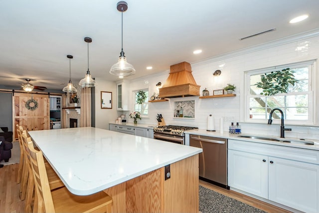 kitchen featuring sink, white cabinetry, a center island, stainless steel appliances, and a barn door