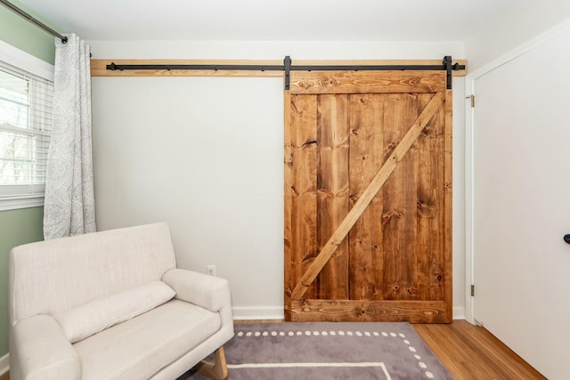 living area with wood-type flooring and a barn door