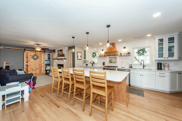 kitchen with sink, white cabinets, custom exhaust hood, a center island, and a barn door