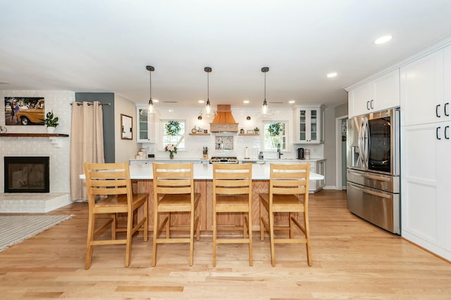 kitchen featuring stainless steel refrigerator with ice dispenser, a kitchen bar, light hardwood / wood-style flooring, a kitchen island, and white cabinets