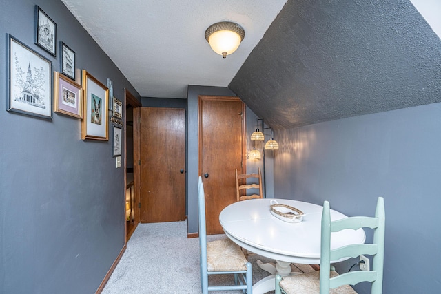 dining area featuring vaulted ceiling, carpet, baseboards, and a textured ceiling