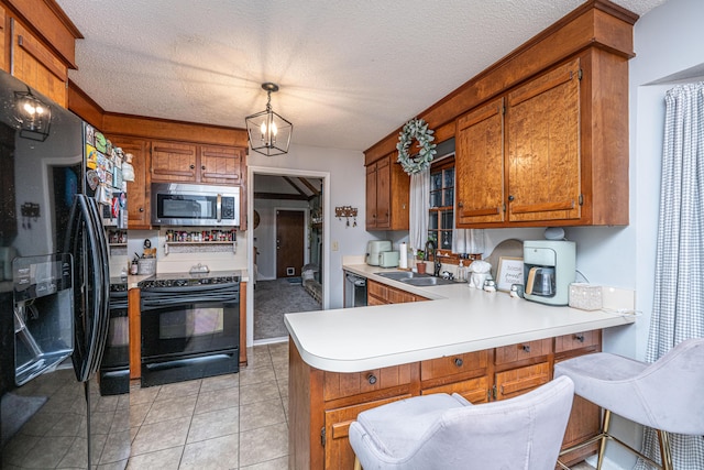 kitchen with black appliances, brown cabinetry, a peninsula, and a sink