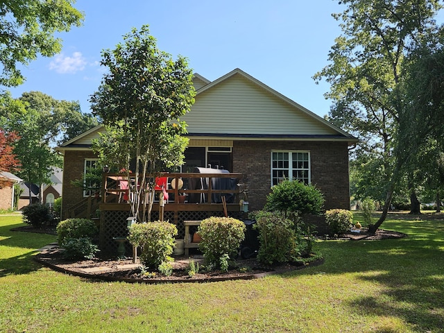 back of property featuring a lawn, brick siding, and a deck