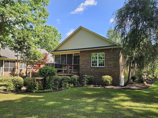 rear view of property with a sunroom, brick siding, and a lawn