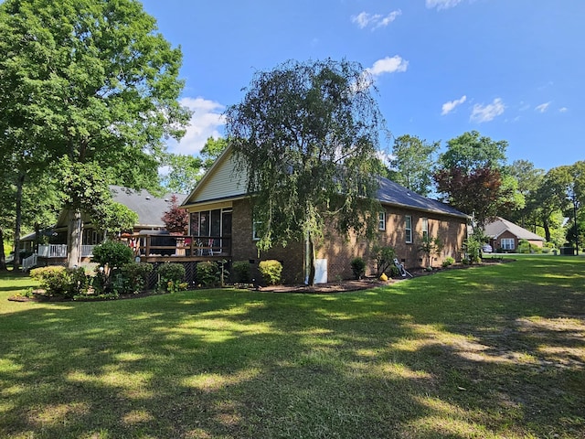back of house featuring a yard, brick siding, and a deck
