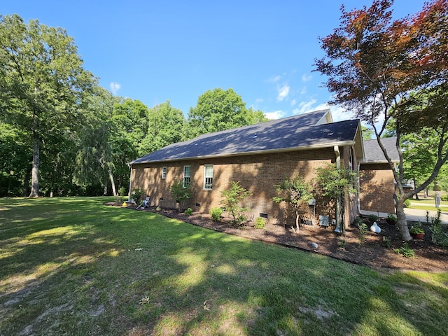 view of side of home featuring crawl space, a lawn, and brick siding