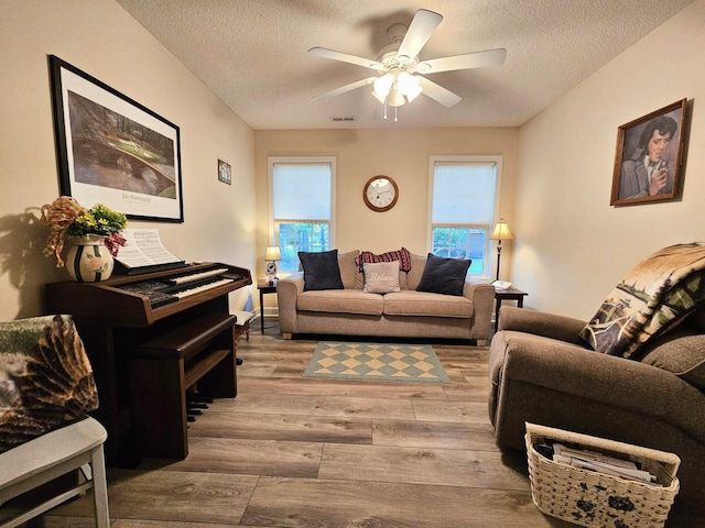 living area with a textured ceiling, wood finished floors, and a ceiling fan