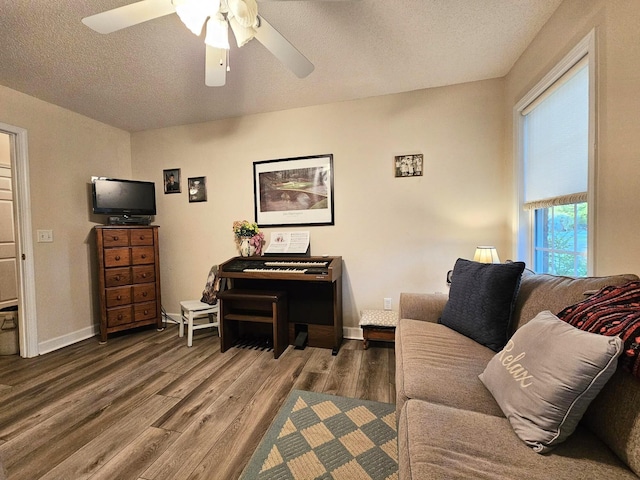 living area with wood finished floors, a textured ceiling, ceiling fan, and baseboards