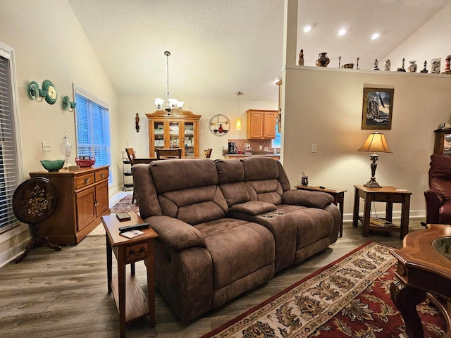 living room with vaulted ceiling, a chandelier, light wood finished floors, baseboards, and recessed lighting