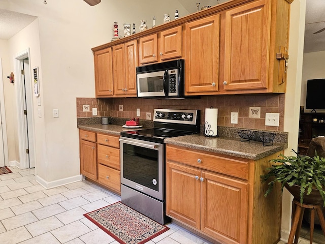 kitchen featuring stainless steel appliances, dark countertops, backsplash, a ceiling fan, and light tile patterned floors
