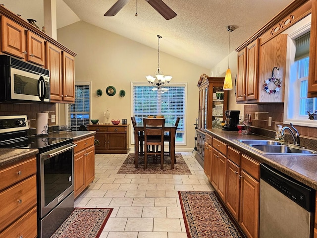 kitchen with stainless steel appliances, a sink, dark countertops, vaulted ceiling, and tasteful backsplash