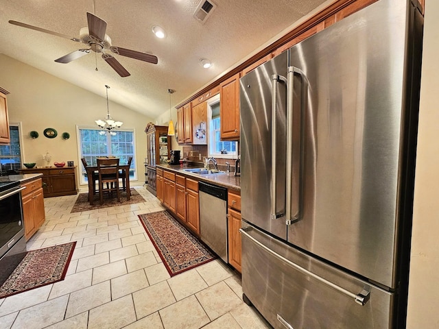 kitchen featuring appliances with stainless steel finishes, vaulted ceiling, a textured ceiling, a chandelier, and dark countertops