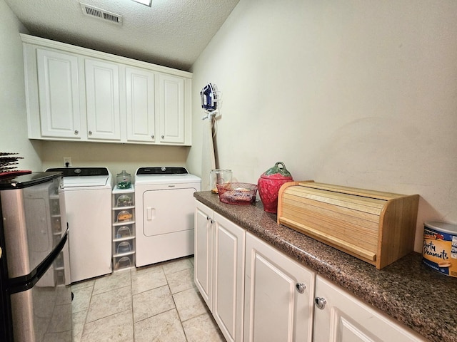 washroom featuring washer and dryer, cabinet space, a textured ceiling, and light tile patterned floors