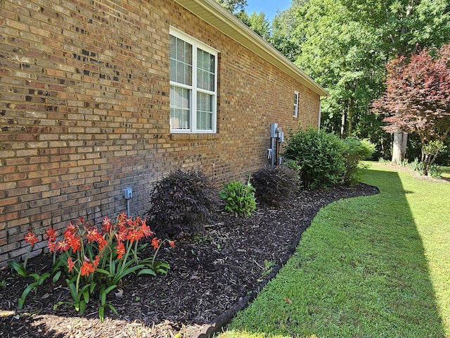 view of side of home featuring a lawn and brick siding