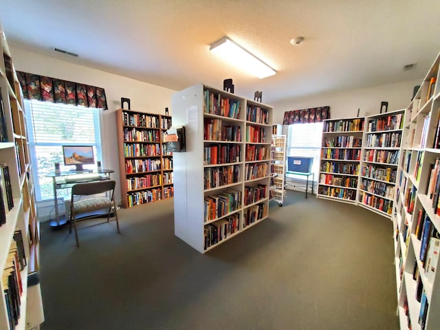 sitting room with wall of books, carpet, and healthy amount of natural light