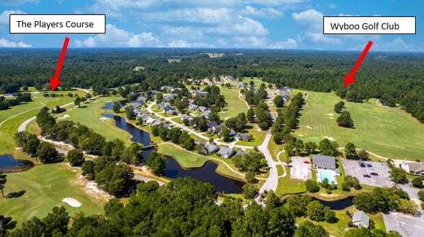 aerial view of property and surrounding area with a forest, a large body of water, and a golf club